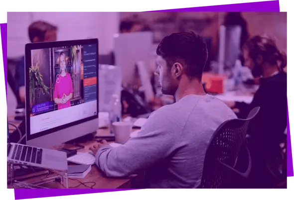 Imagem com filtro roxo de um homem sentado assistindo um curso em vídeo Descola no computador